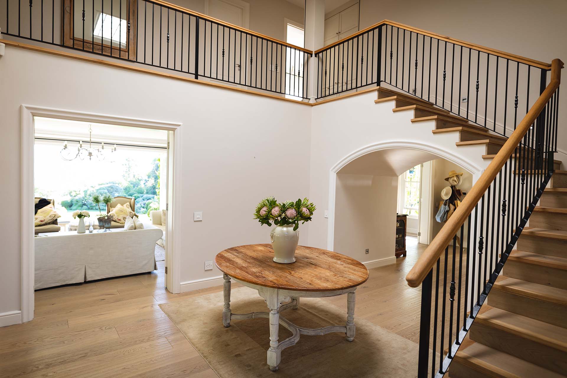 General view of house interior with table and vase with flowers in spacious hallway and staircase. modern interiors and house decoration concept.