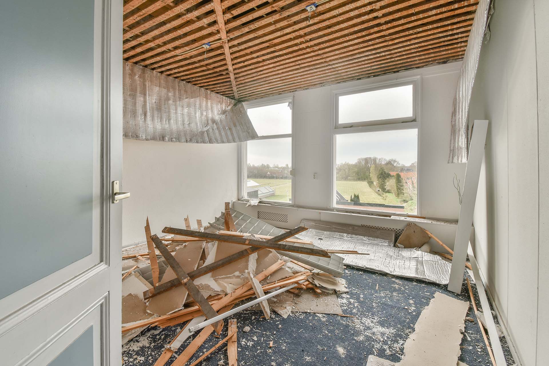 Interior of empty white room with large balcony windows with curtains and wooden parquet floor