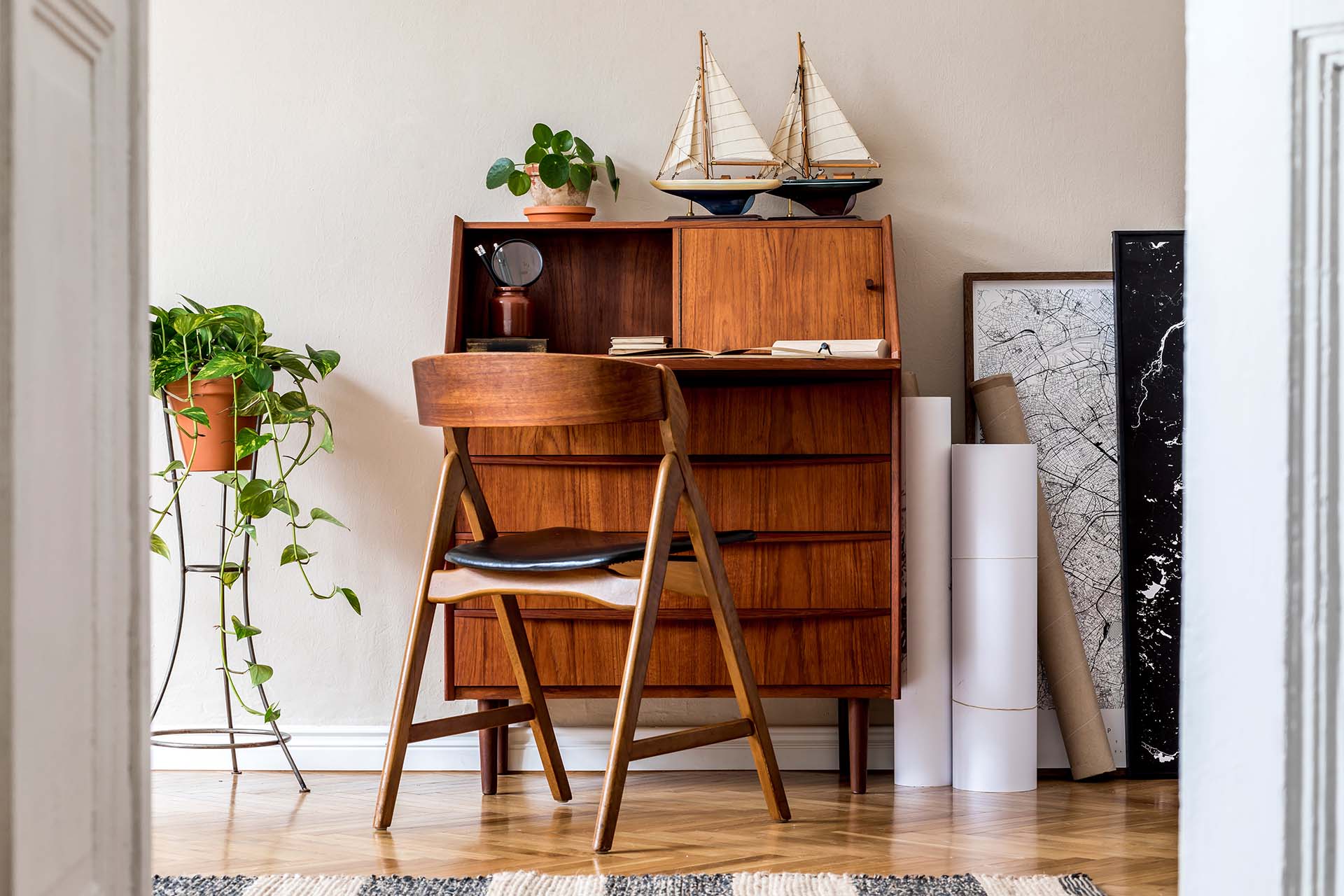 Stylish and vintage interior design of living room with wooden retro commode, plants, ships, map and elegant personal accessories. Mock up poster frame on the wall. Template. Home decor.